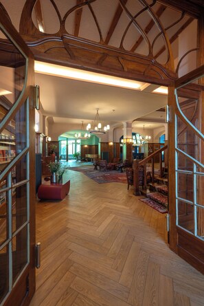 Un vestíbulo espacioso con suelo de madera, una imponente escalera y un gran candelabro.