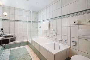 Een moderne badkamer met een bad, douche en wastafel.