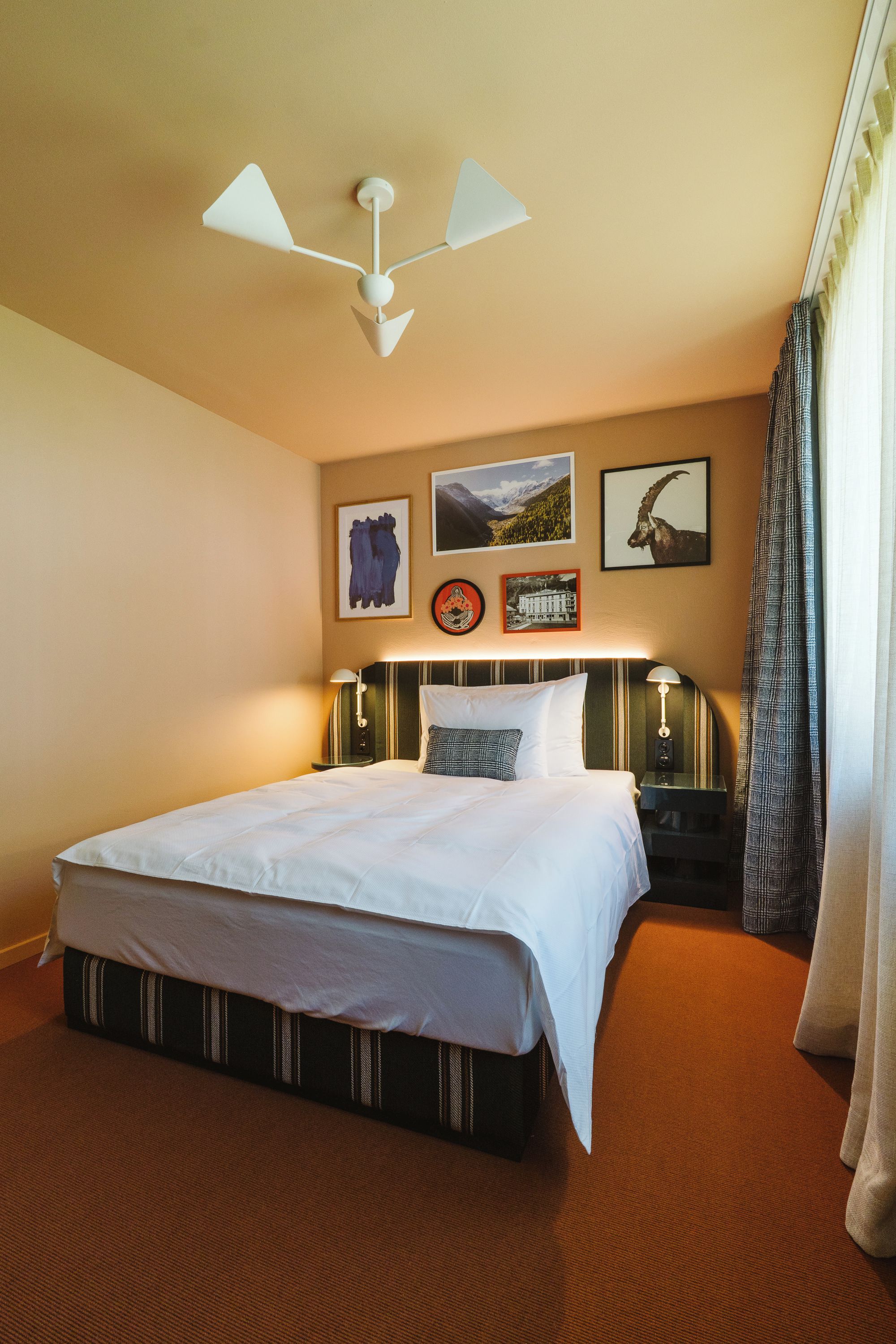 Une chambre d’hôtel avec un grand lit, une table de chevet, une lampe et un luminaire au plafond.