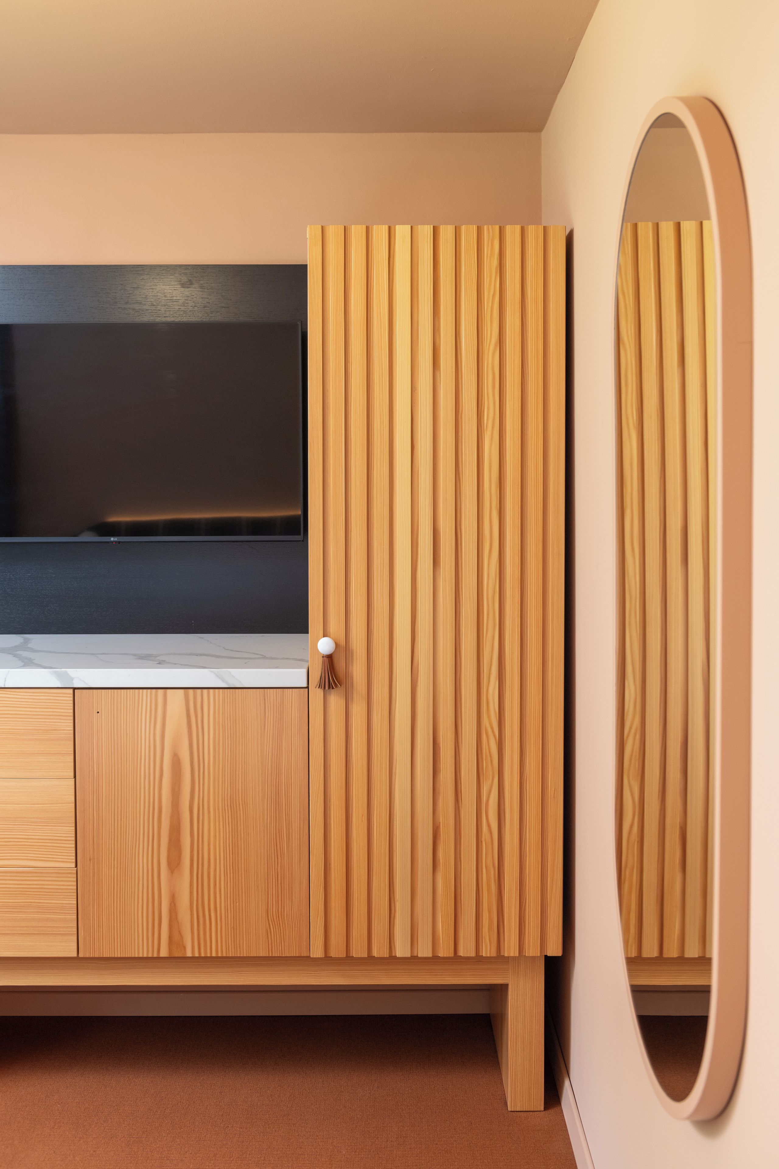 Ein Holzkleiderschrank mit Spiegel und Flachbildfernseher.