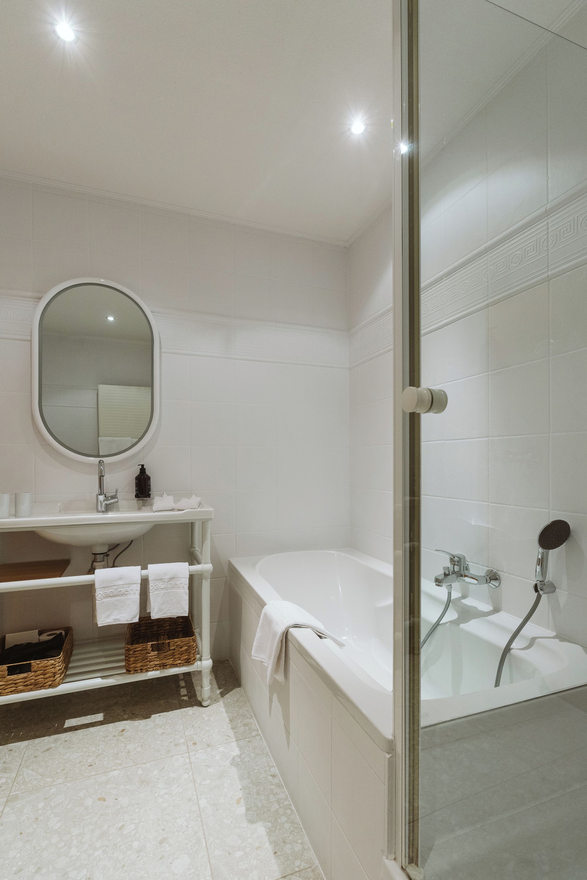 A modern bathroom with a bathtub, a glass-enclosed shower, a sink with a mirror, and a towel rack.
