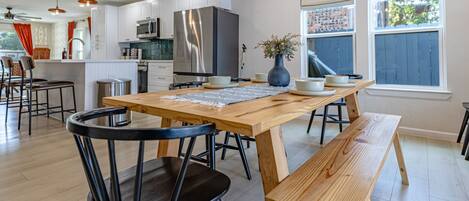 A modern kitchen with a wooden table, black chairs, and a stainless steel refrigerator.