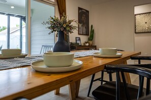 A dining table with white bowls and plates, a vase with flowers, and black chairs. - The Axelrod | Sleeps 16 (Houston)