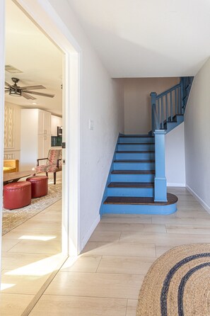 A staircase with blue steps and a wooden handrail, leading to a landing. - The Axelrod | Sleeps 16 (Houston)