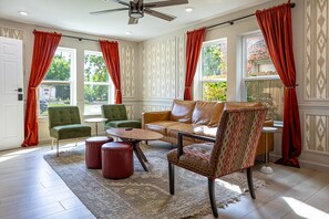 A spacious living room with a sofa, chairs, a coffee table, and a patterned rug. - The Axelrod | Sleeps 16 (Houston)