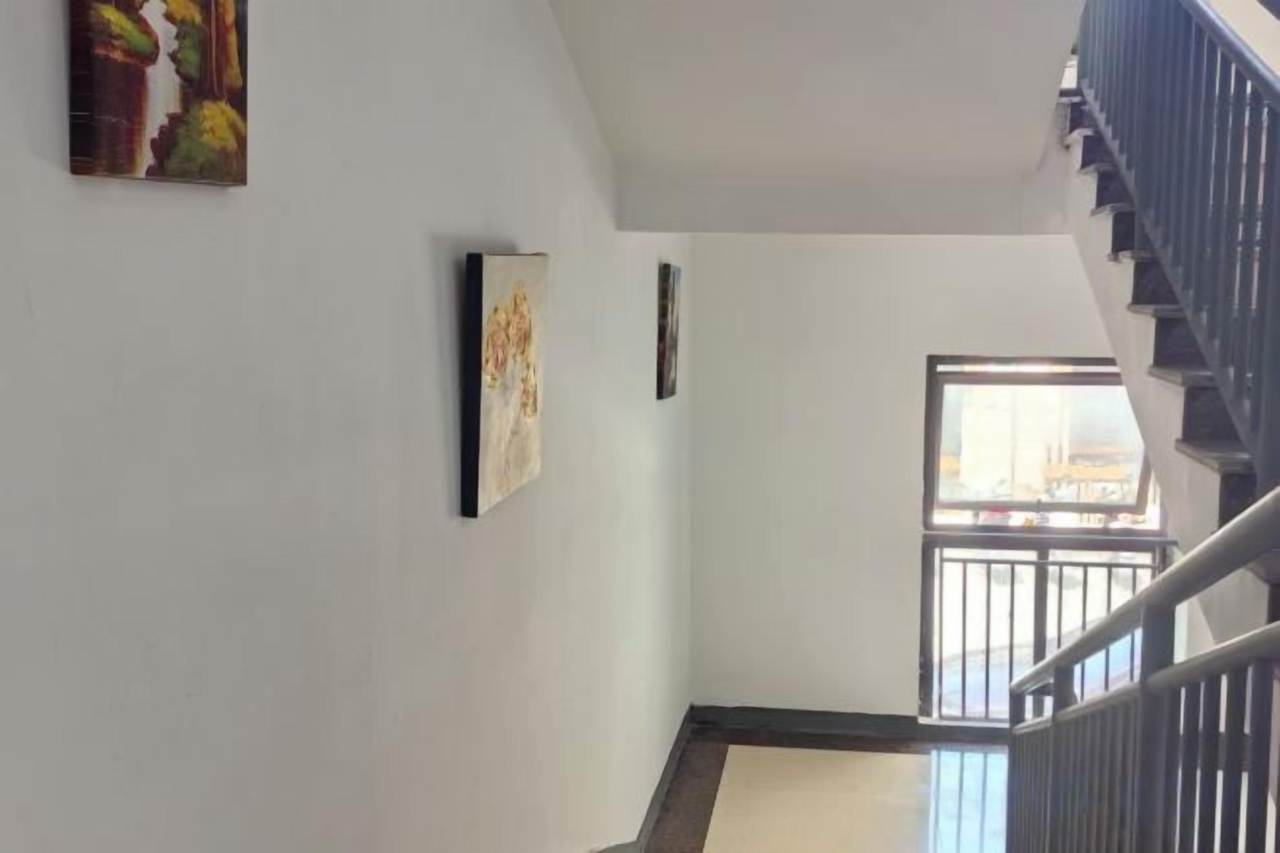 A staircase with a handrail, a window with a view, and a wall with two framed artworks.