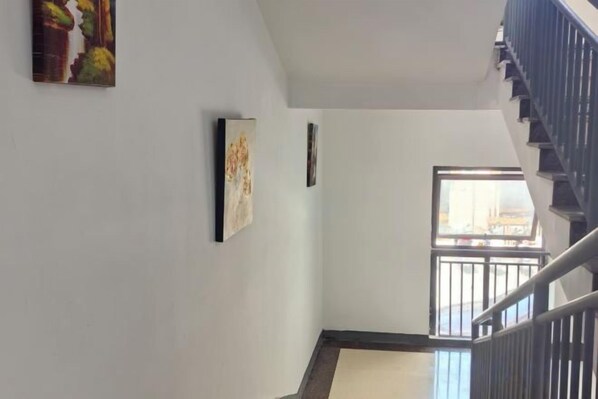 A staircase with a handrail, a window with a view, and a wall with two framed artworks. - Rlan Boutique Hotel (Shanghai)