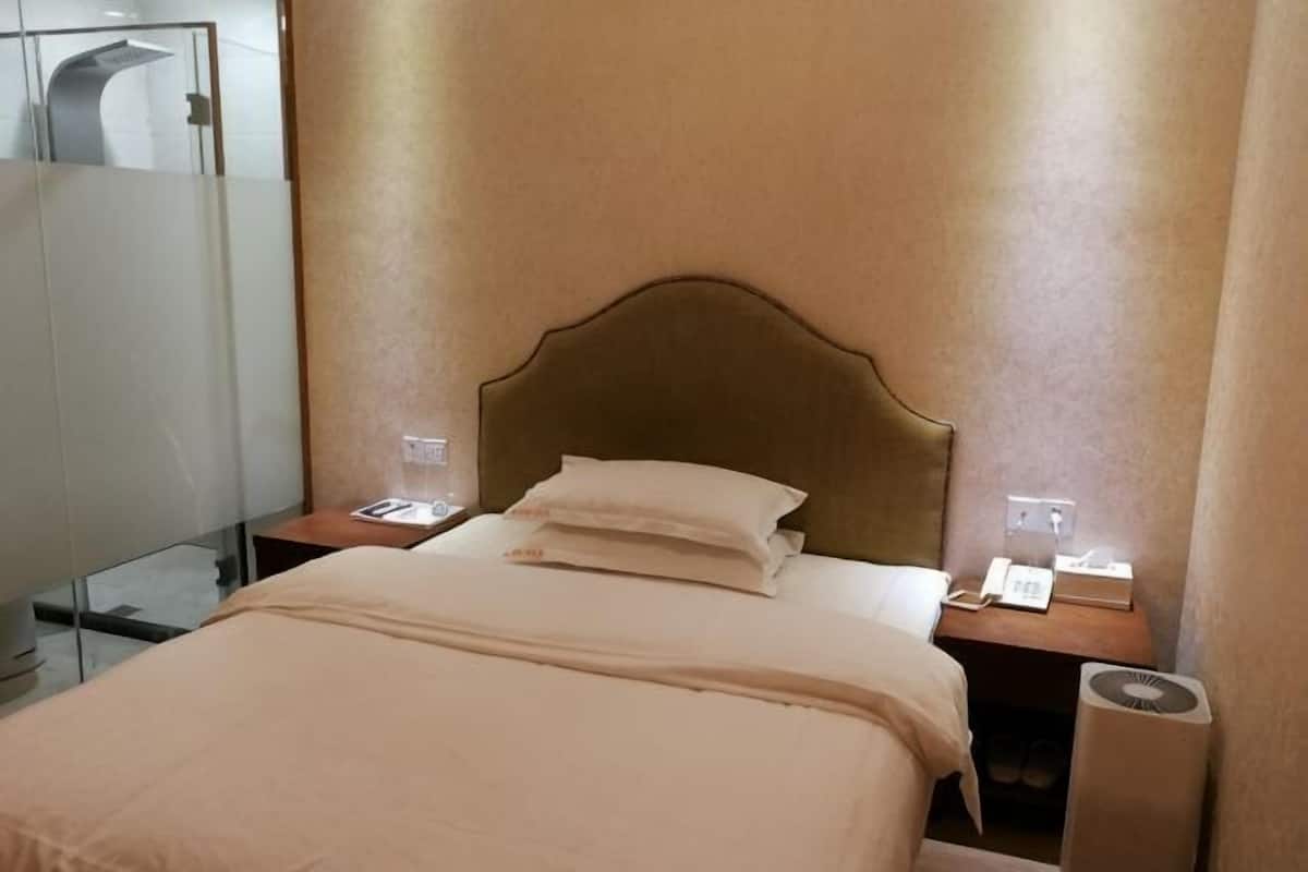 A hotel room with a bed, bedside tables, a mirror, and a wall-mounted telephone.