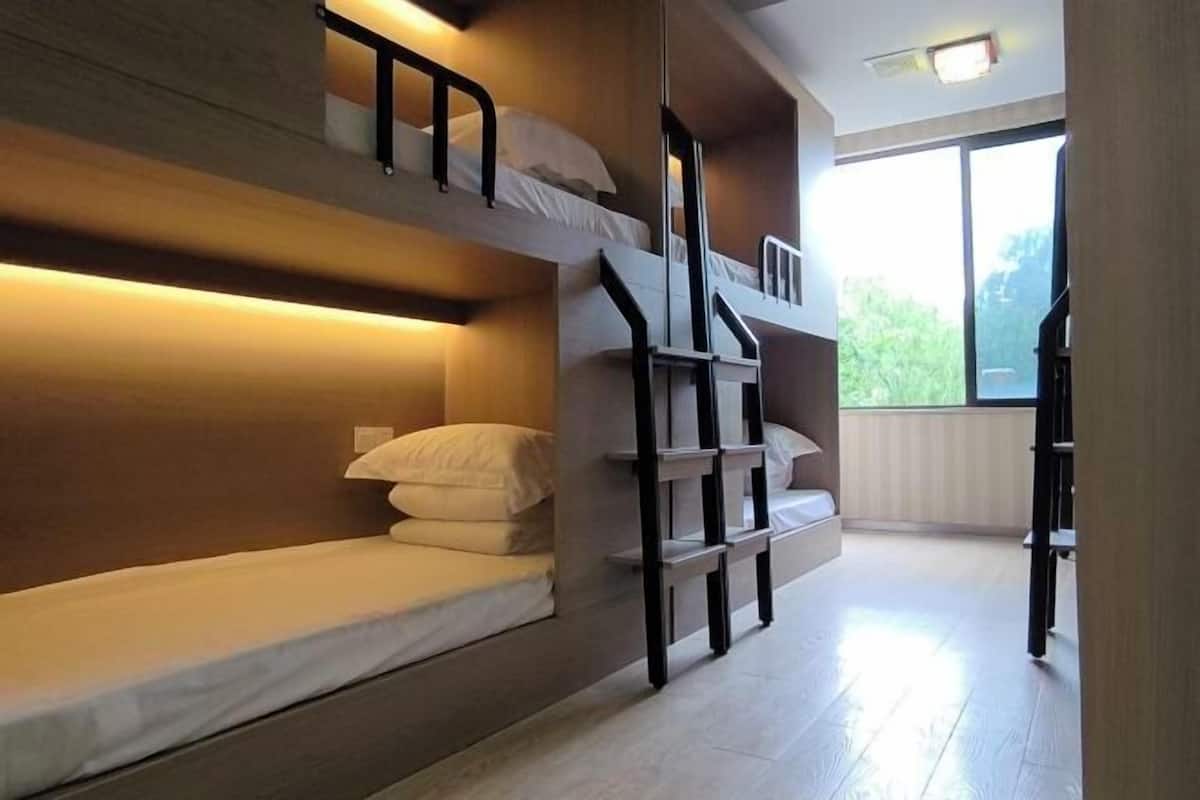 A bunk bed room with a wooden headboard, a staircase, and a large window.