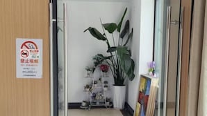A hotel room with a no smoking sign, a potted plant, a small shelf with decorative items, and a painting on the wall. - Rlan Boutique Hotel (Shanghai)