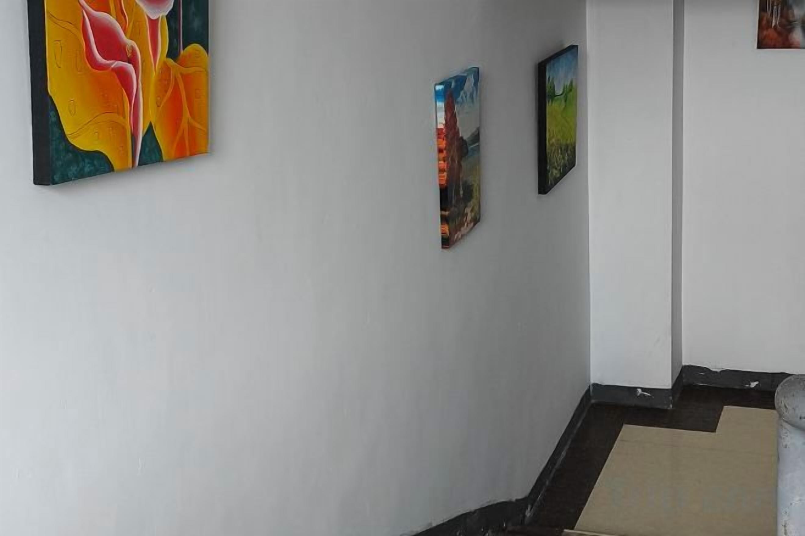 Escada com corrimão e parede decorada com três obras de arte emolduradas.