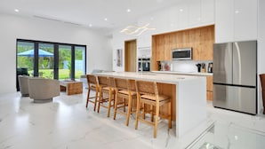 Une cuisine moderne dotée d’un îlot central, de meubles en bois et d’appareils électroménagers en acier inoxydable.