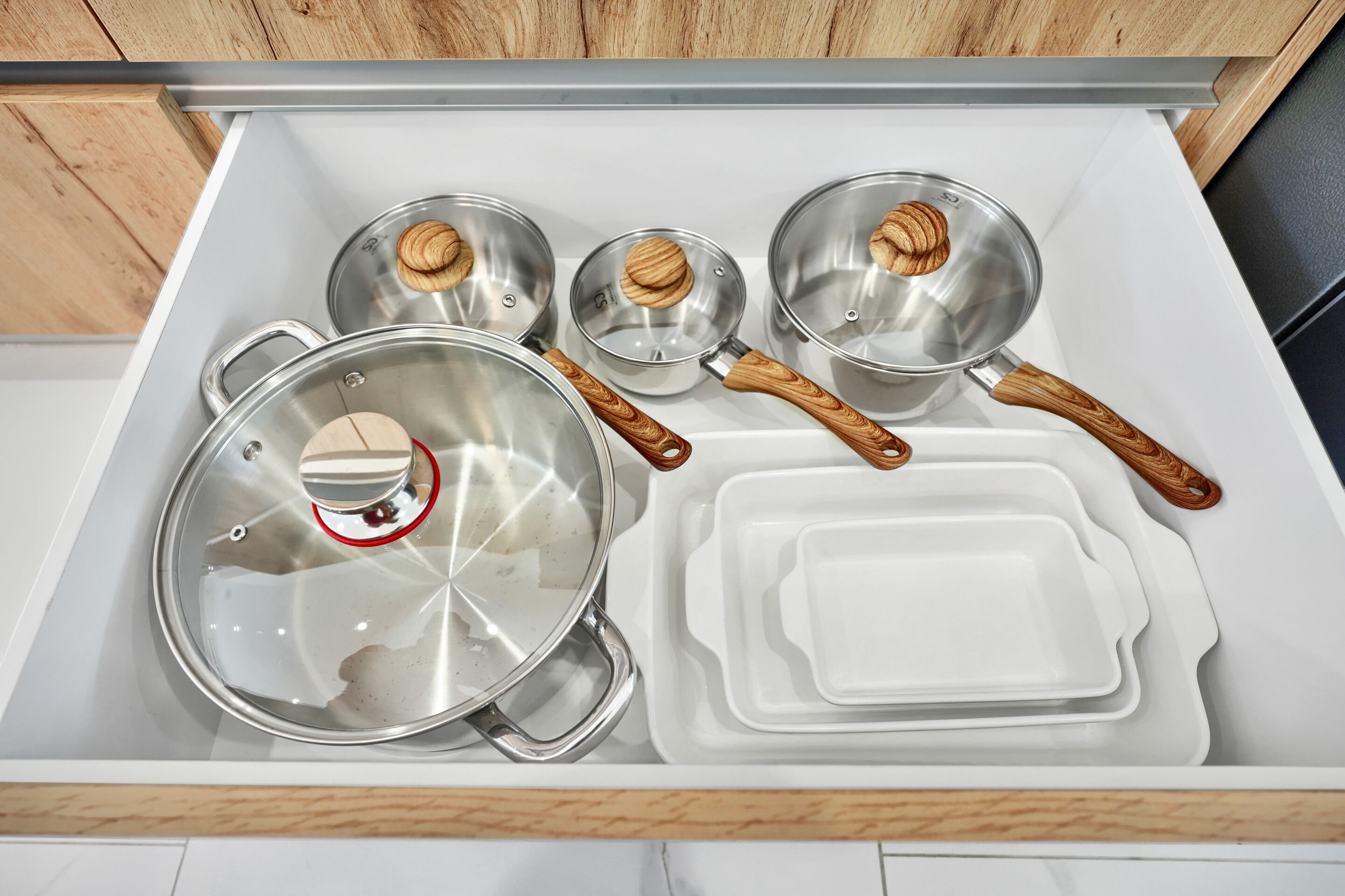 A kitchen drawer with pots, pans, and serving dishes.