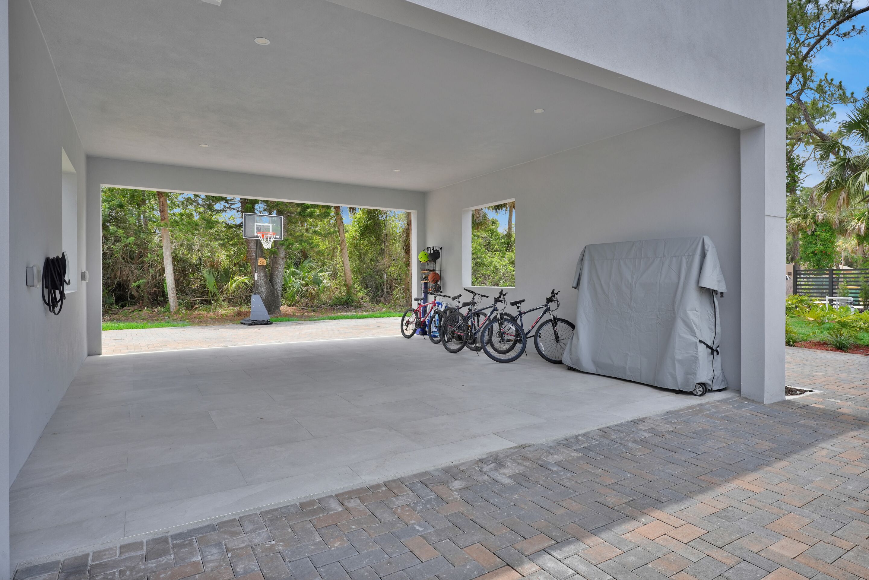 A covered outdoor area with a basketball hoop, bicycles, and a covered bike rack.