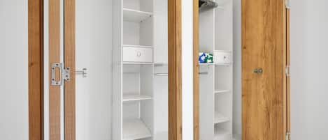 Armario vestidor con puertas abiertas, mostrando estantes y espacio para colgar.