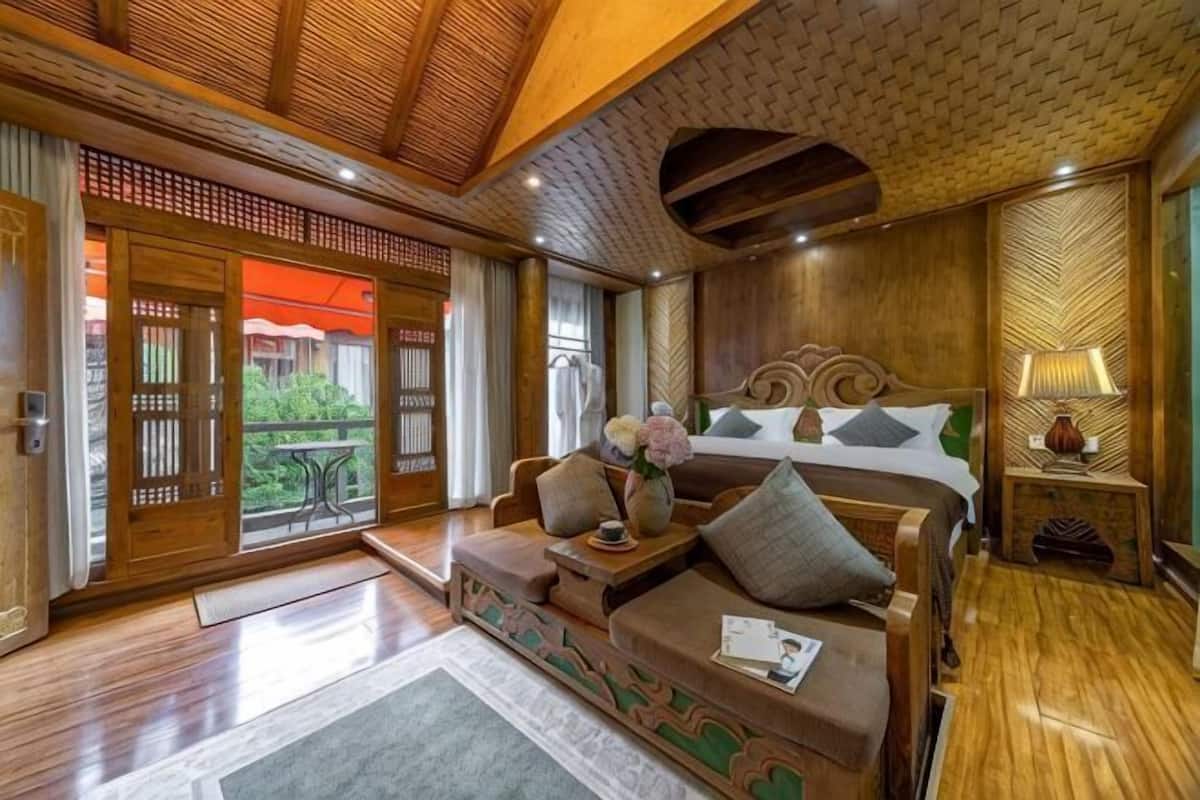 A traditional room with a wooden ceiling, a bed with pillows, a nightstand, and a sofa.