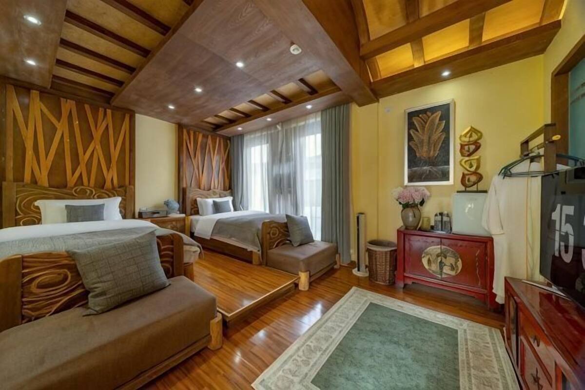 A room with a bed, a sofa, a small table, a cabinet, and a television.