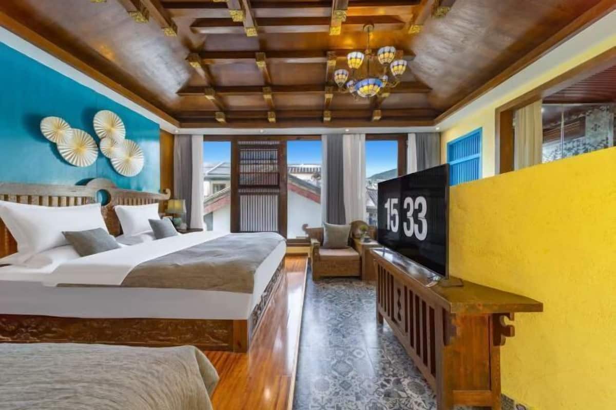 A hotel room with a large bed, a TV, and a view of the outside.