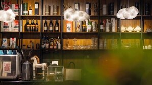 Un espace bar avec des étagères remplies de bouteilles, de verres et un appareil à café.