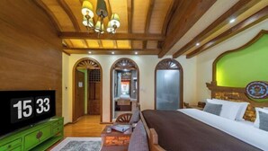 Une chambre d’hôtel avec un grand lit, une télévision, un plafond en bois et un mur vert.