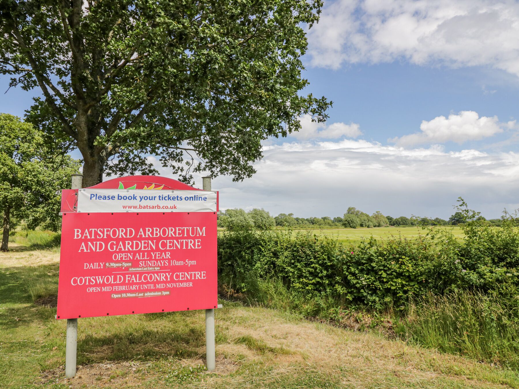 A sign for Batsford Arboretum and Garden Centre, open daily from 9:30 am to 5 pm, and Cotswold Falconry Centre, open from mid-February to mid-November.