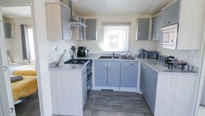 A compact kitchen with grey cabinets, a stove, and a microwave. - Casa De Rhu (Evesham)
