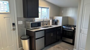 A compact kitchen with a microwave, coffee maker, and stove. - Charming Tiny House minutes from Syracuse! (Syracuse)