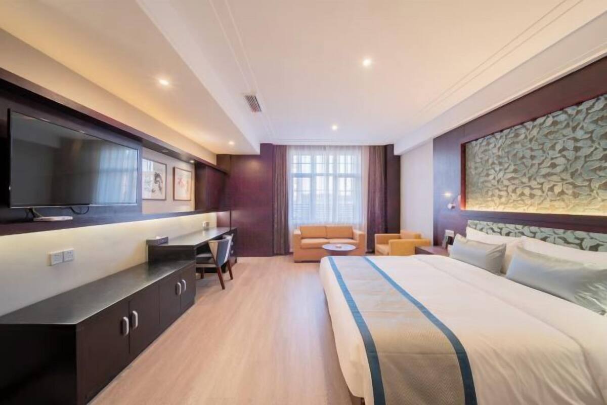 Een hotelkamer met een bed, bureau, televisie en een bank.