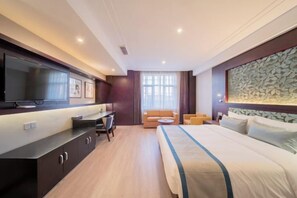 A hotel room with a bed, a desk, a television, and a sofa. - Kunlun Hotel (Nantong)