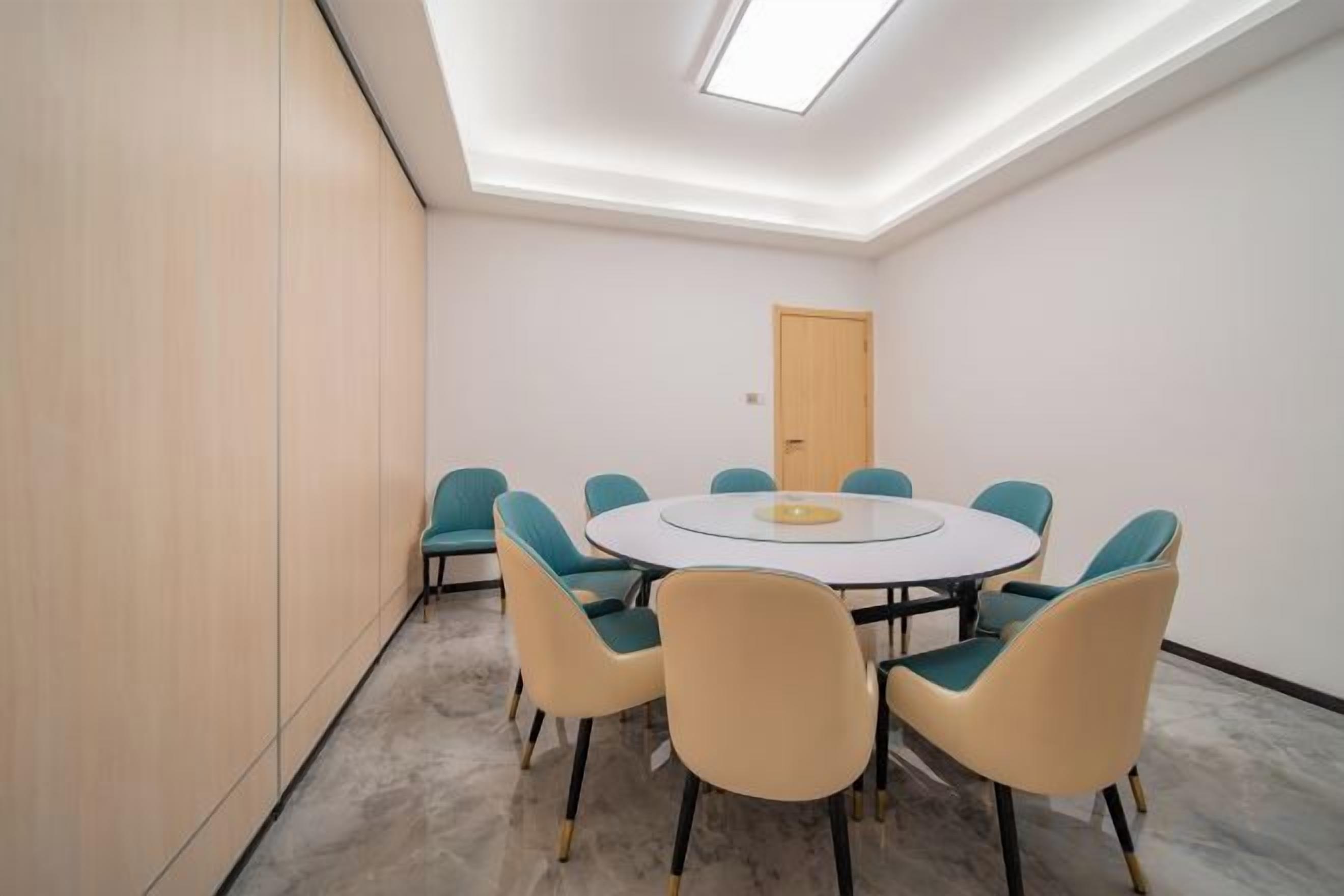A conference room with a round table, six chairs, and a door in the background.