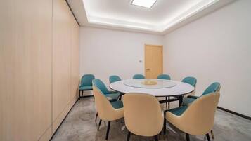 A conference room with a round table, six chairs, and a door in the background.
