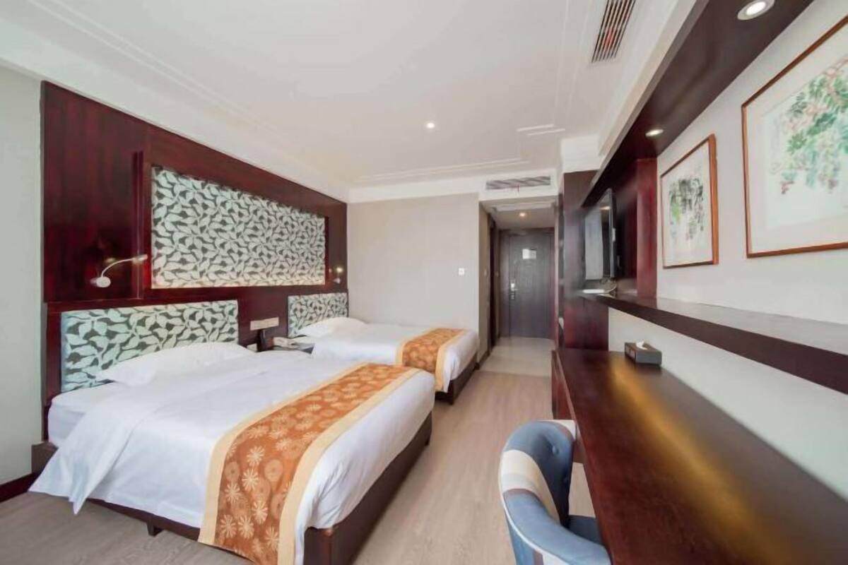 Een hotelkamer met twee bedden, een bureau, een stoel en een televisie.
