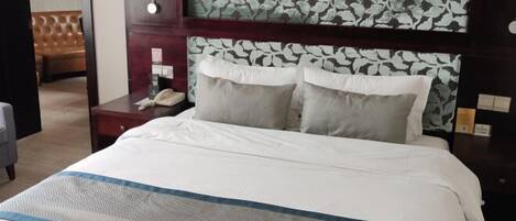 Ein Hotelzimmer mit einem Bett, einem Nachttisch mit Telefon und einer Wand mit Blumenmuster.