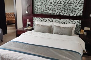 Habitación de hotel con cama, mesita de noche con teléfono y pared con estampado floral.