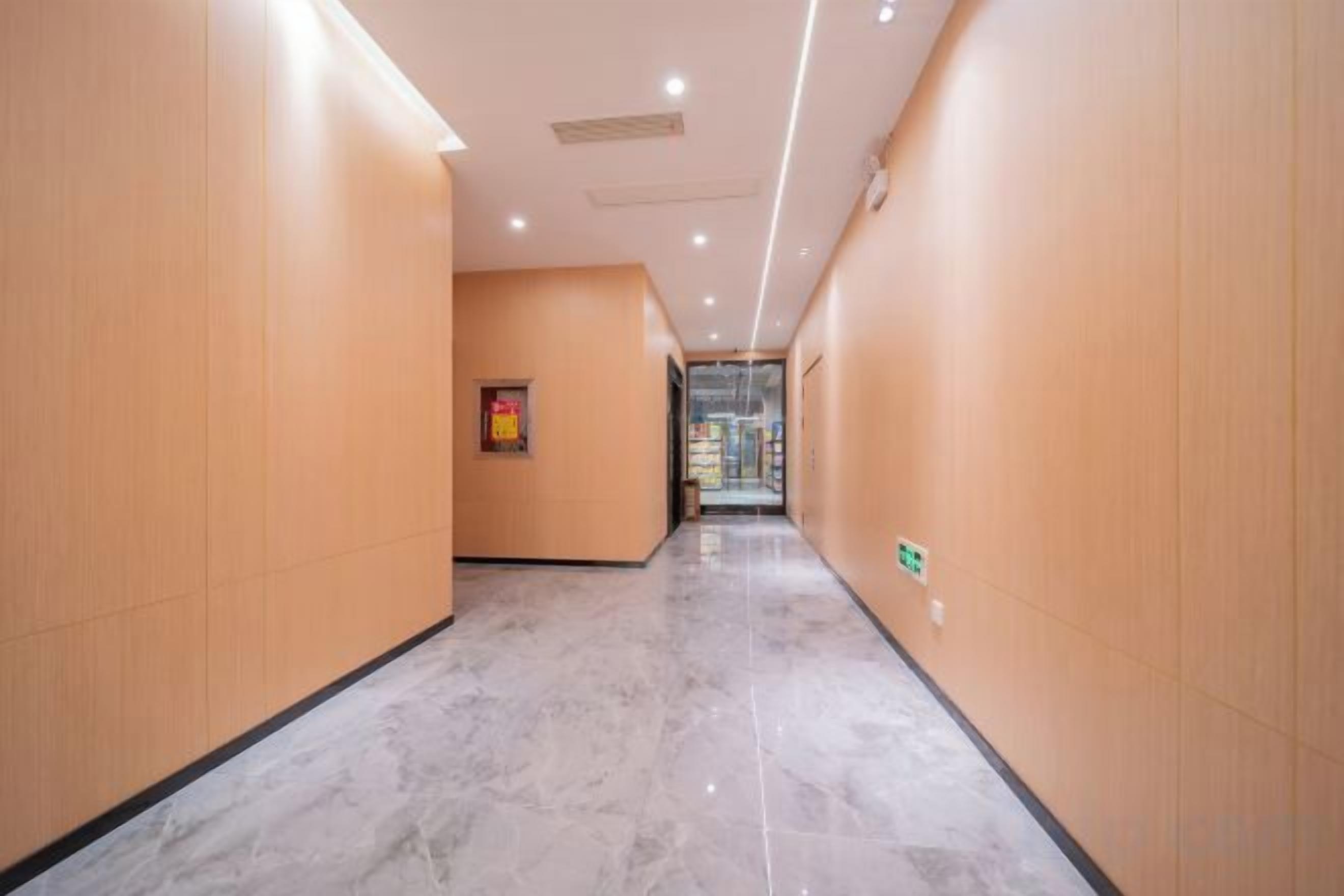 A hallway with wooden walls and a marble floor, leading to a glass door.