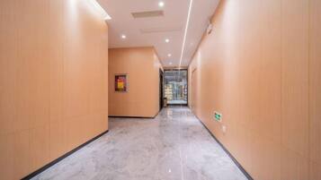 A hallway with wooden walls and a marble floor, leading to a glass door.