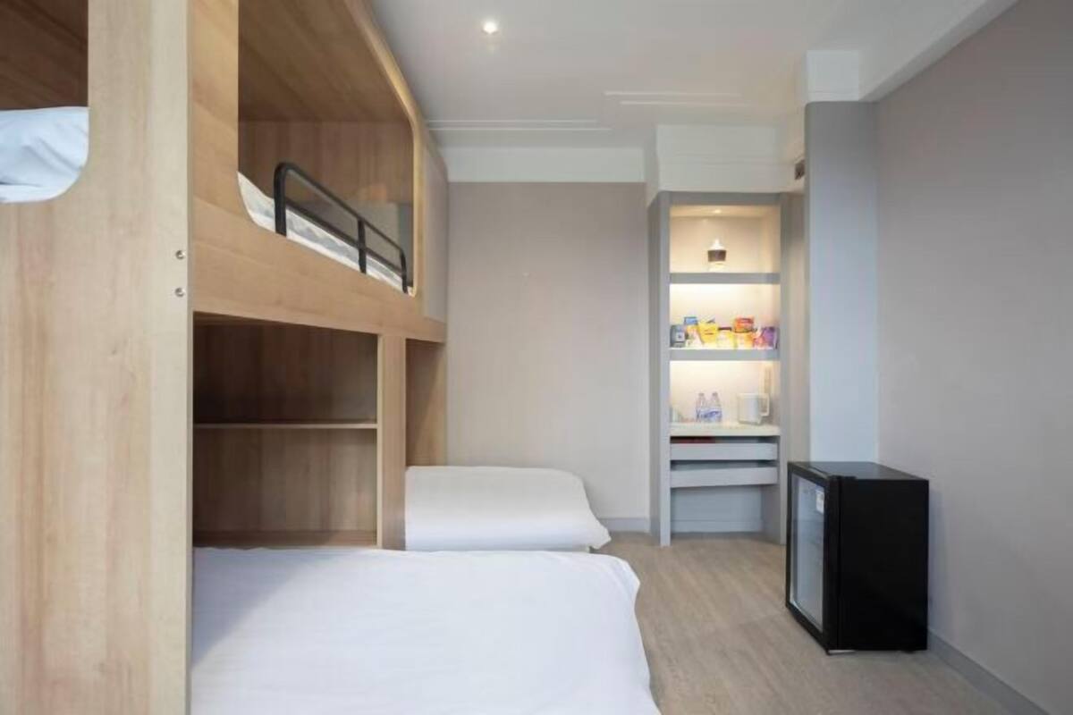 Een compacte hotelkamer met stapelbedden, een kitchenette en een kleine koelkast.