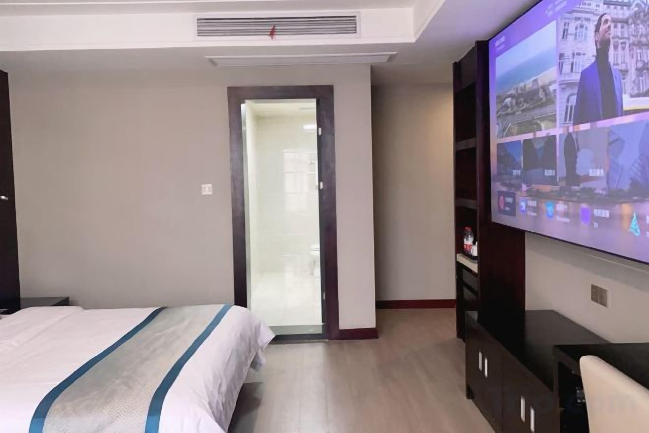 Ein Hotelzimmer mit einem Bett, einem Fernseher und einer Tür zu einem weiteren Raum.