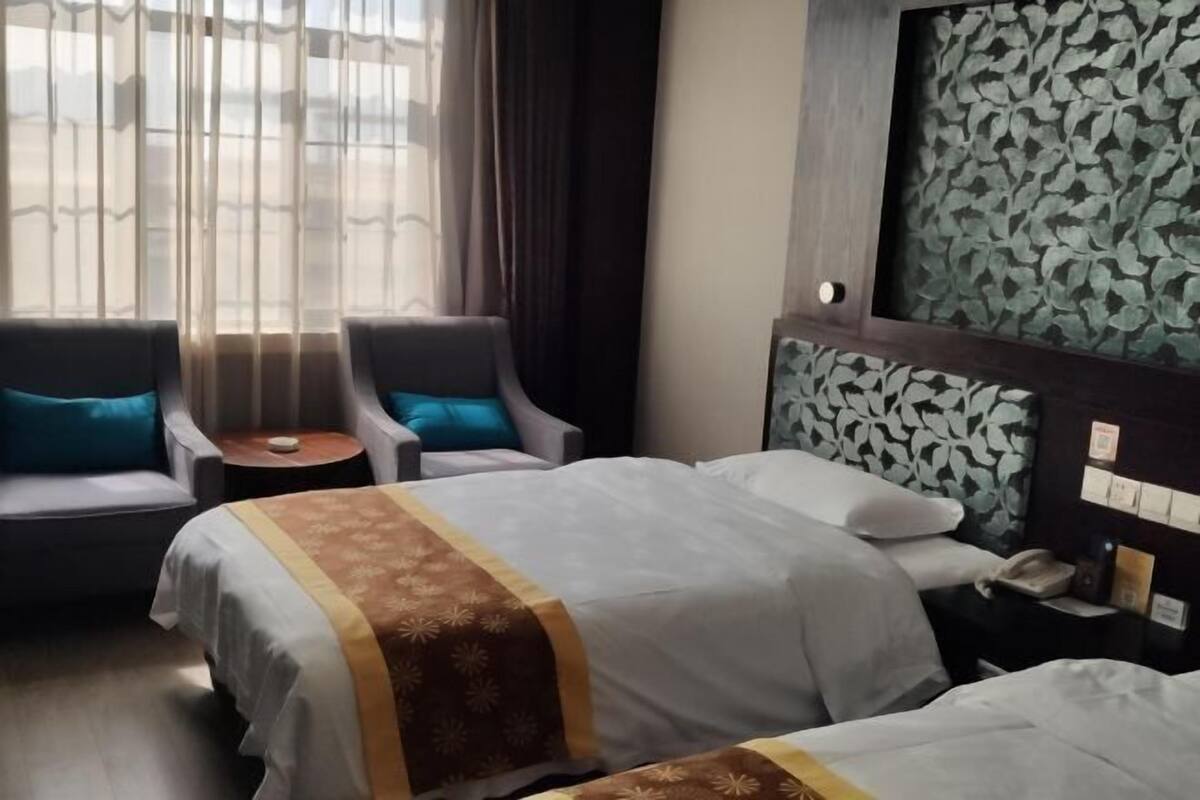 Een hotelkamer met twee bedden, een kleine tafel en twee fauteuils.