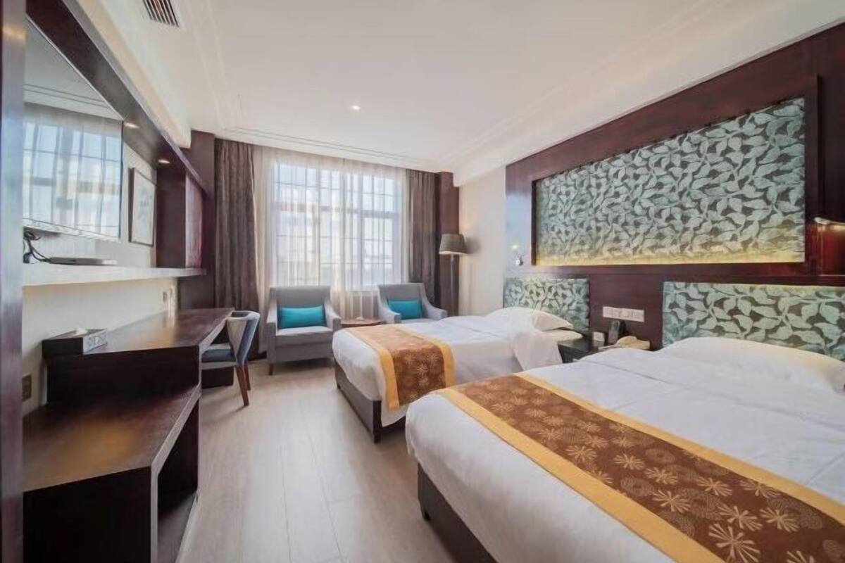 Een hotelkamer met twee bedden, een bureau, een stoel en een groot raam.