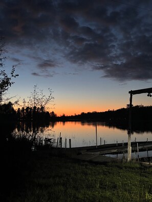 A serene lakeside view with a wooden dock and a metal railing.