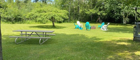 Un espacio para picnic con una mesa y sillas, rodeado de árboles y césped.