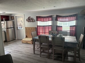 Een ruimtelijke woonruimte met een kitchenette, een eethoek met een tafel en stoelen, en een bed met hoofdeinde.