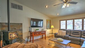 A cozy living room with a fireplace, a sofa, a coffee table, and a TV mounted on the wall.