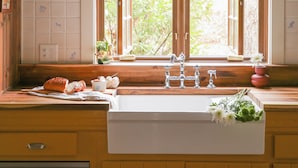 Una cocina con un ventanal grande, vigas de madera y un lavatorio con varios grifos.