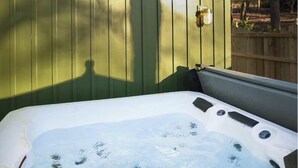 Un jacuzzi con un muelle de madera y un cobertizo verde al fondo.