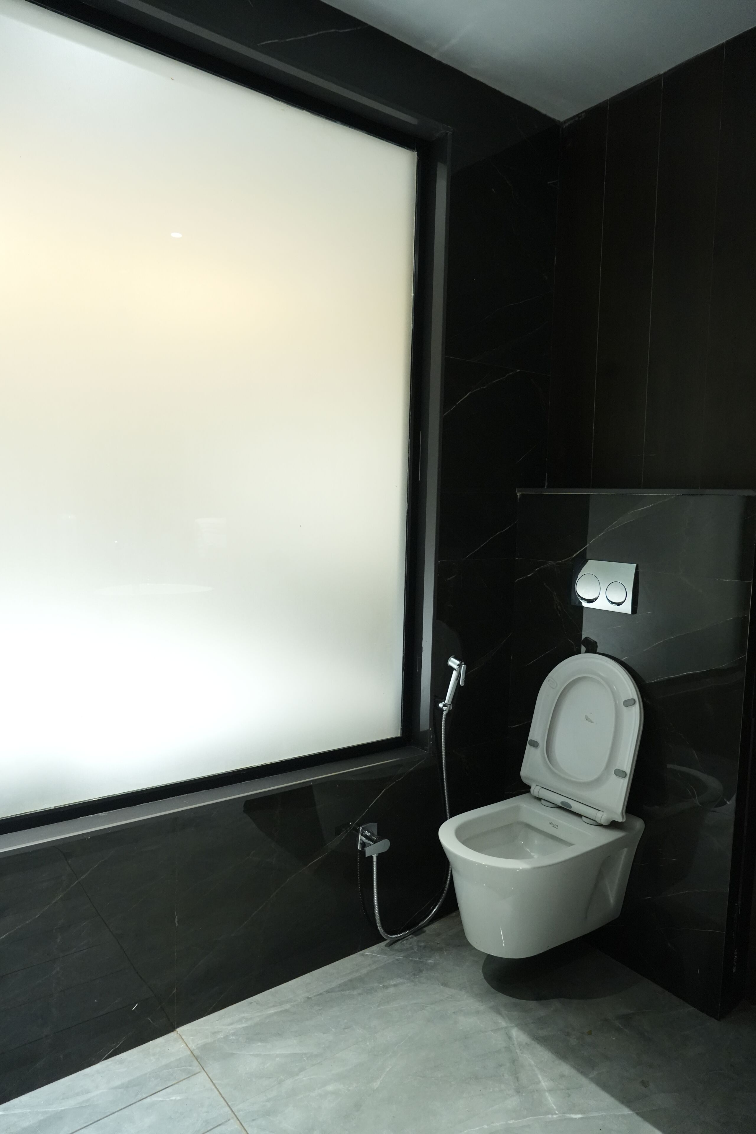 A modern bathroom with a toilet, a shower, and a large window.