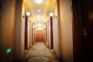 A hotel hallway with carpeted floors, wall sconces, and doors leading to rooms. - Aofeng Hotel (Xuancheng)