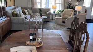 A spacious living room with a round wooden dining table, two sofas, and a chandelier.