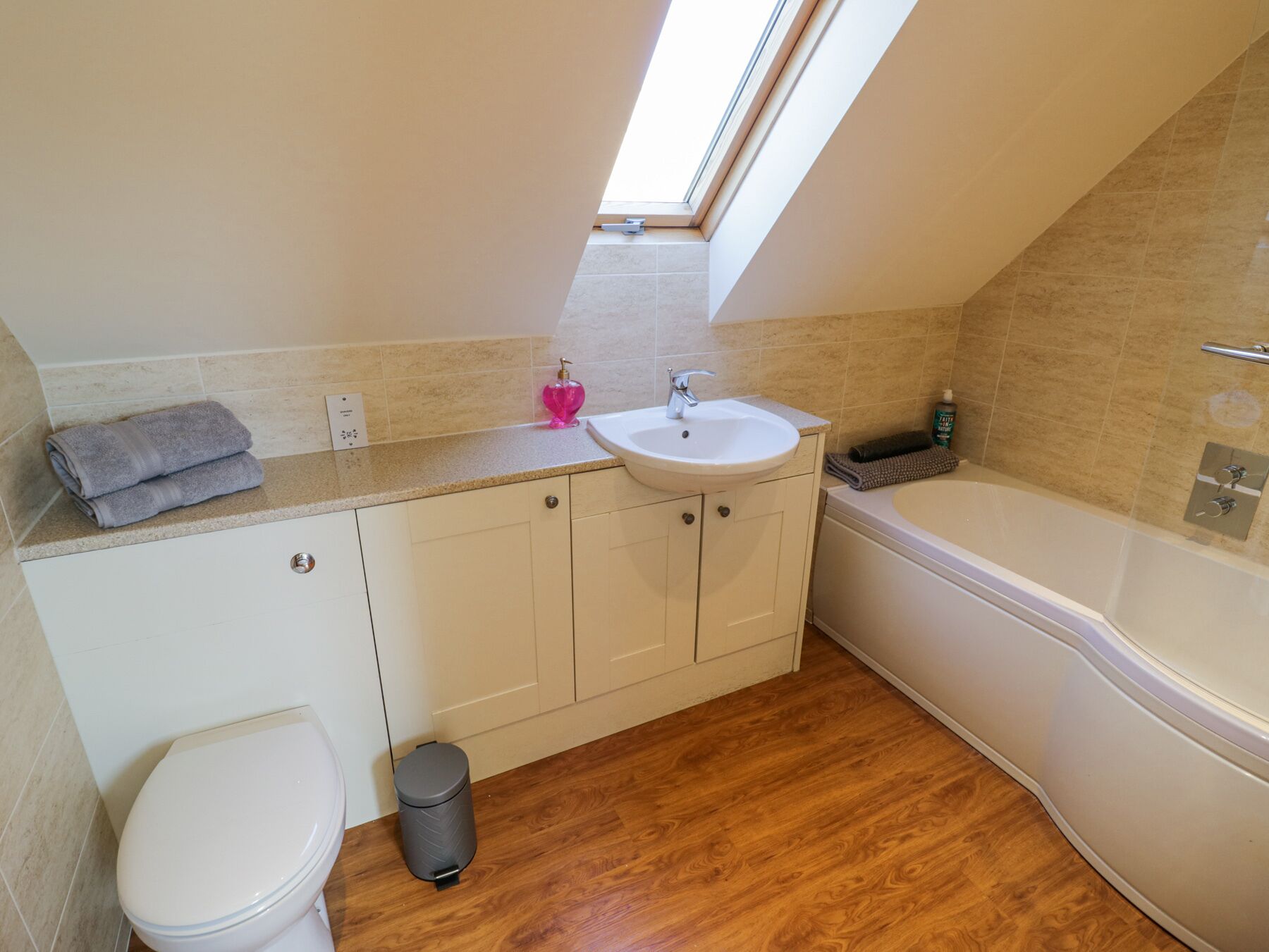 Une salle de bain moderne avec un puits de lumière, un lavabo, des toilettes et une baignoire.